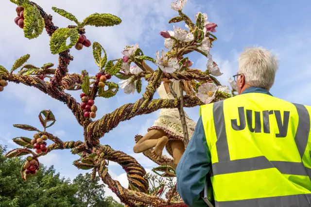 Jurylid bekijkt een fruitkunstwerk