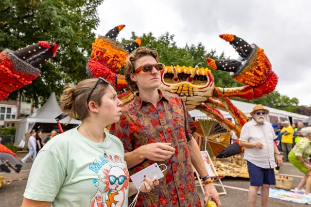 Twee bezoekers bij een groot fruitkunstwerk