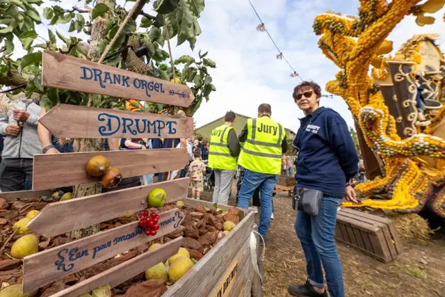 Bezoekers en juryleden naast een fruitkunstwerk
