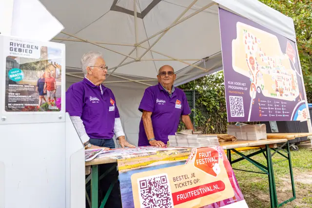 Twee medewerkers bij de informatiestand van het festival