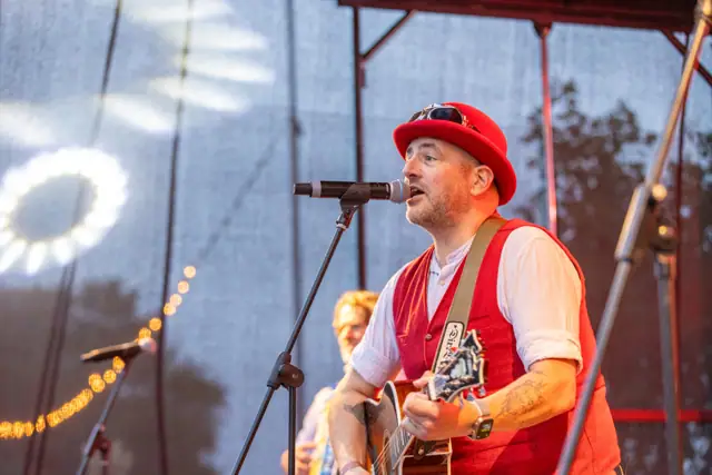 Muzikant met rode hoed en gitaar op het podium